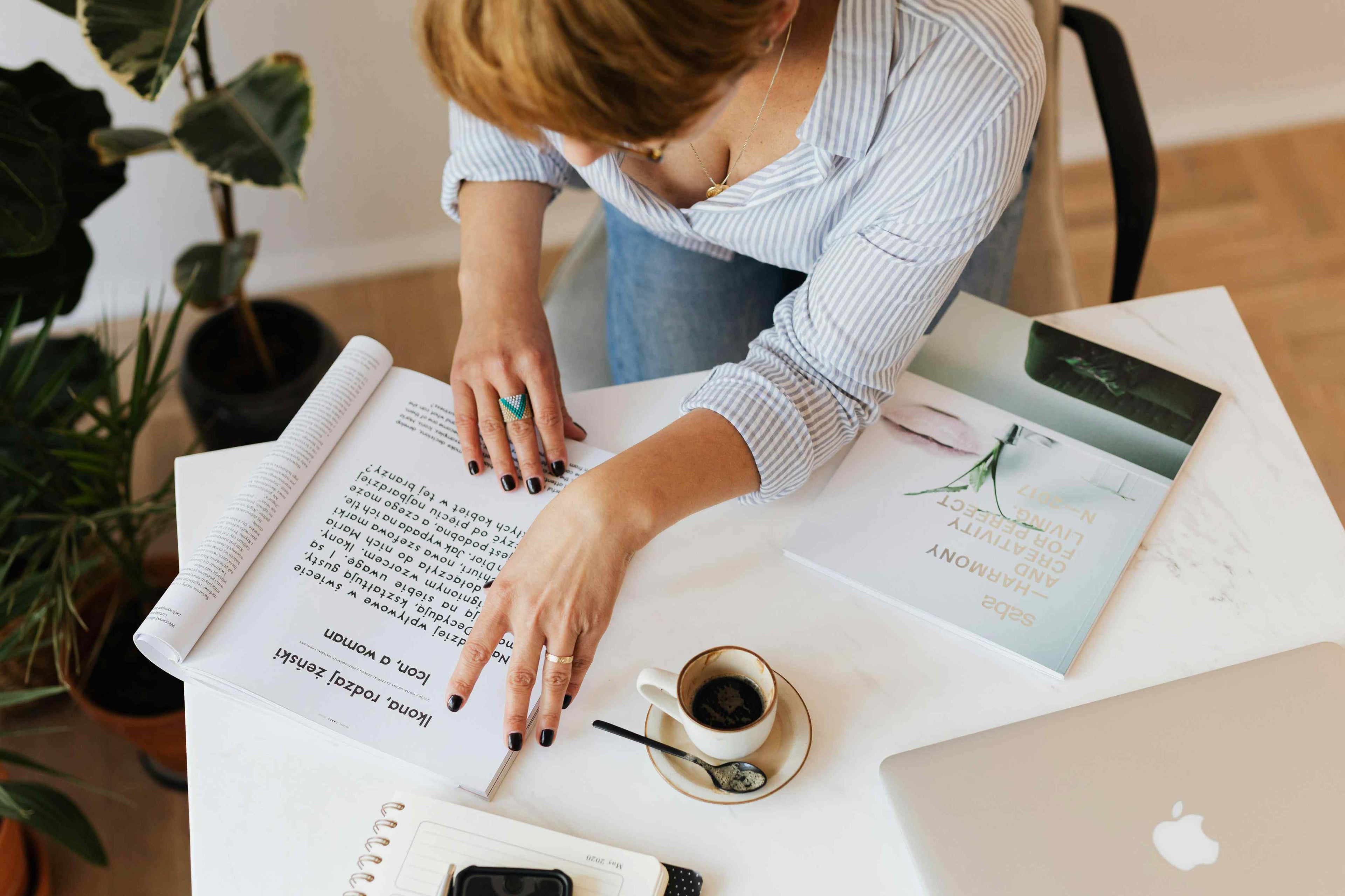 Person working at a desk with a laptop, notebook, and coffee cup.